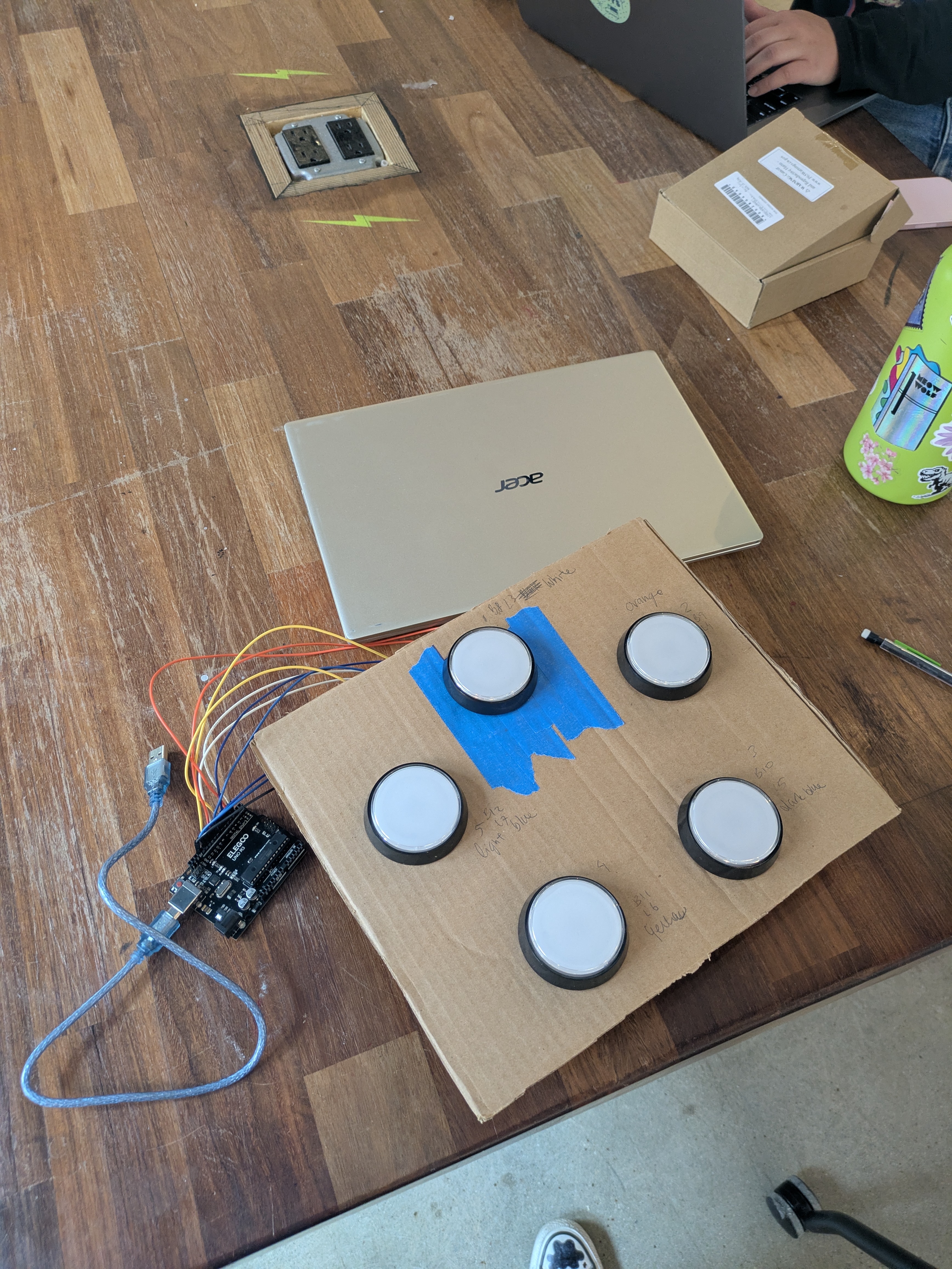plastic arcade buttons screwed into a piece of cardboard