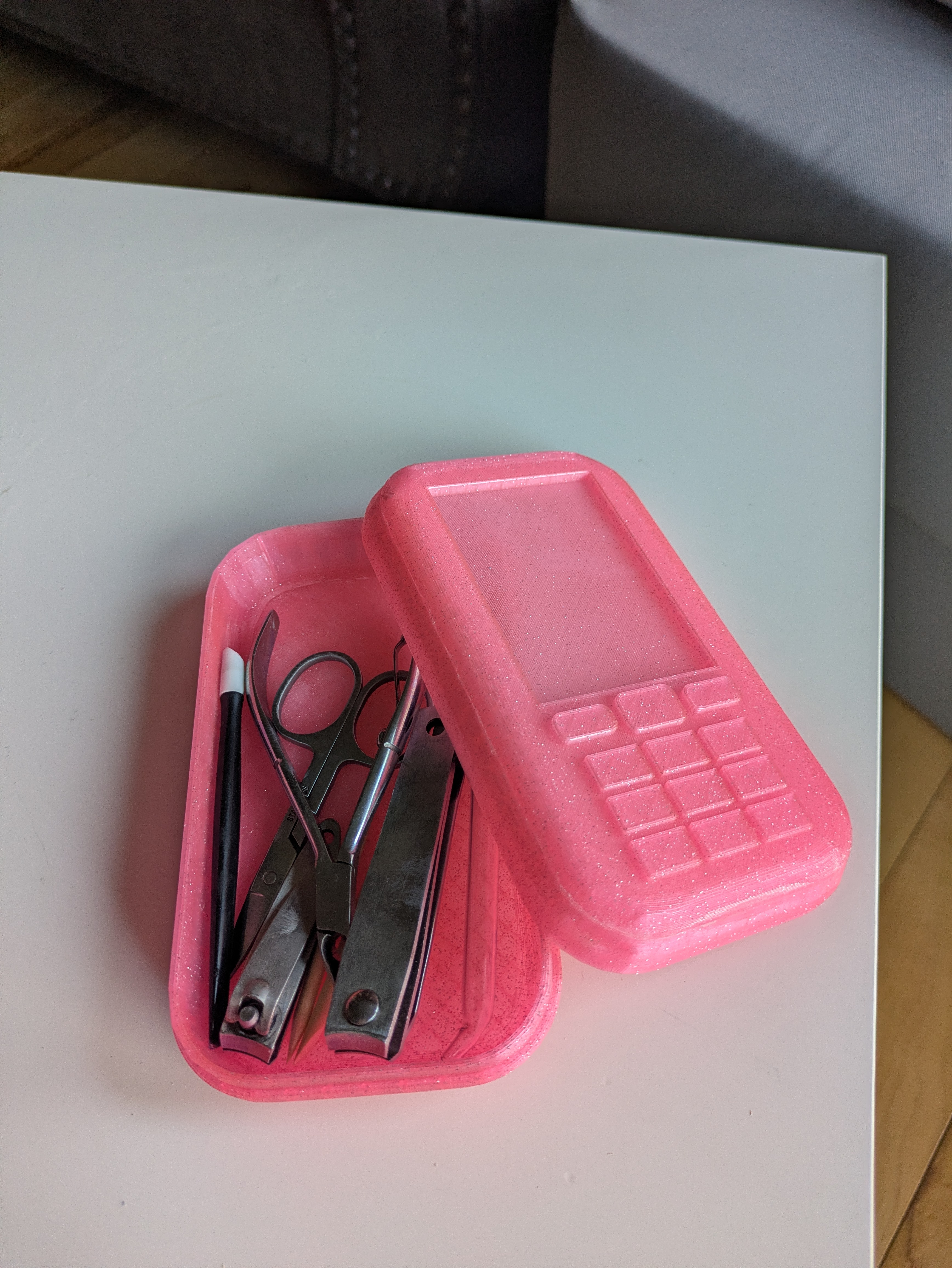 a hot pink, sparkly 3d printed trinket box shaped like a cell phone holding nail tools